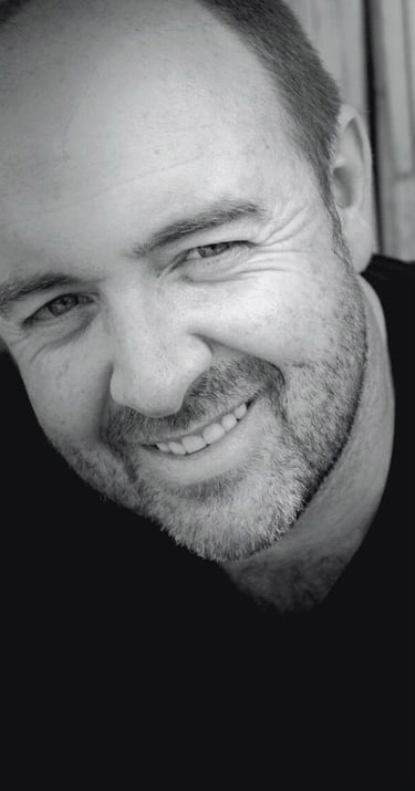 Portrait of Martin Osner, South African artist and photographic artist, smiling in black and white