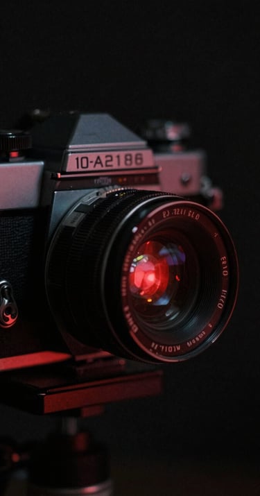 Close up of a 1960s film camera, high contrast noir lighting, deep black shadows #1A1A1A, grainy film texture, red #D4202B spotlight reflecting on the lens, Nouvelle Vague cinema vibe.