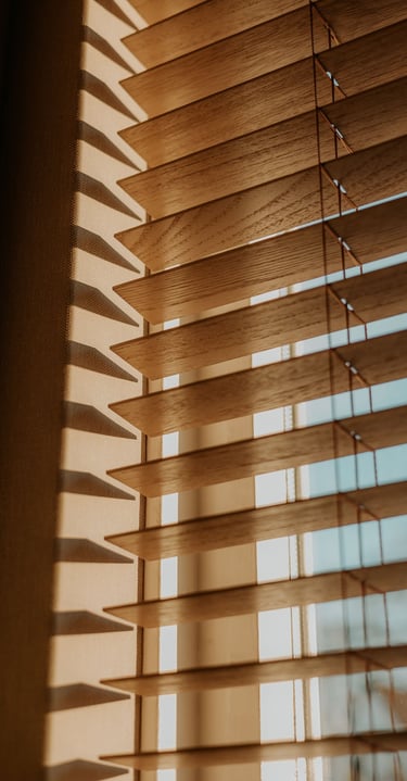 Natural wood horizontal window blinds with sunlight filtering through for home decor.