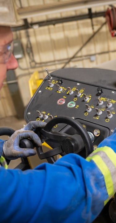 A heavy equipment technician is inspecting the hydraulic settings on a Bomag paving machine's digital dashboard 