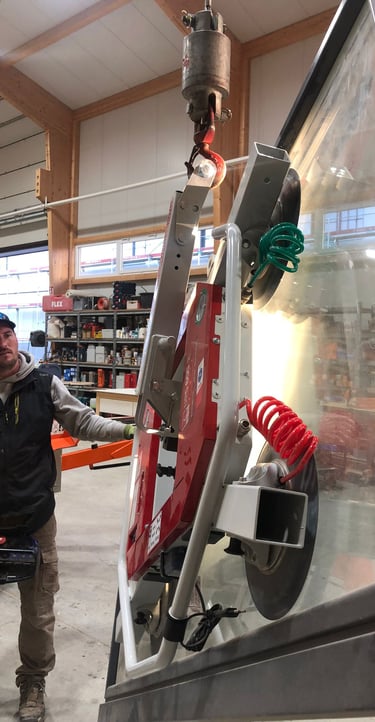 Schreinermeister Ferdinand Volk mit Glasscheibe am roten Vakuum-Saugheber in der Halle.