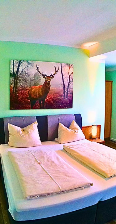 Cozy hotel room with a double bed, mint green walls, and a large stag painting above the headboard.