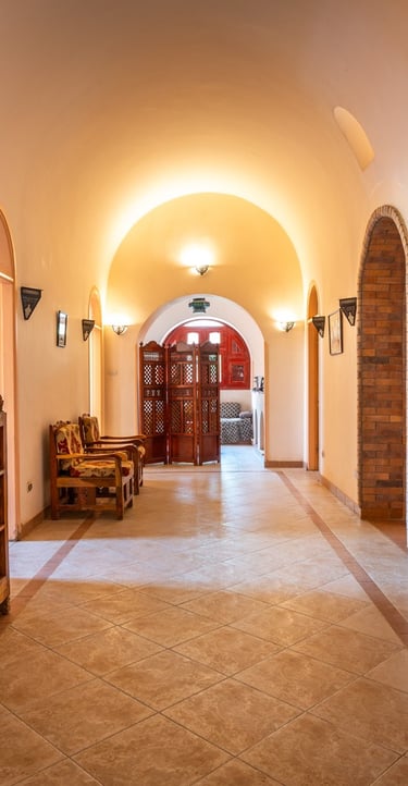 Elegant nubian style villa hallway with arched ceilings, tiled floors, and rustic wooden furniture.