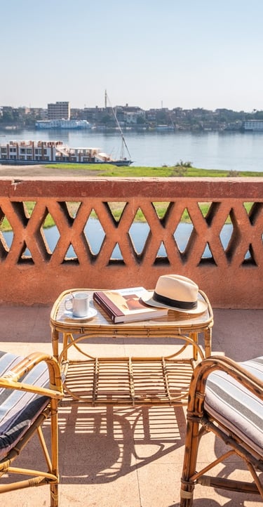 Luxury balcony terrace with wicker chairs overlooking a scenic Nile River cruise in Egypt.