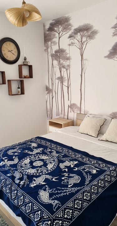 a bed with a blue blanket and a clock on the wall