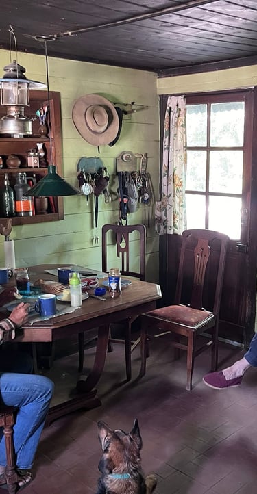 Three people and a dog are in a rustic room with wooden walls.