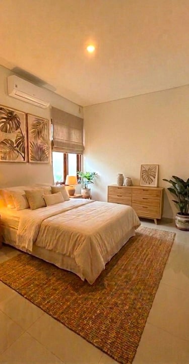 Modern tropical bedroom interior with warm lighting, wood furniture, and botanical leaf wall art.
