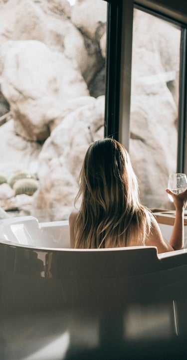 eine Frau in einer Badewanne mit einem Glas Wein