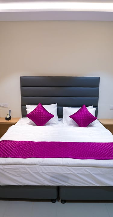 Modern hotel room with a queen bed, purple accents, and air conditioning.