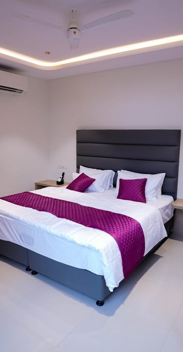 Modern hotel room featuring a king bed with purple accents and ambient cove lighting.
