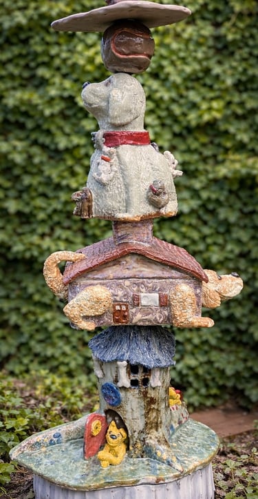 A vertical ceramic totem pole featuring a stack of various dog breeds accented with vibrant glazes. 