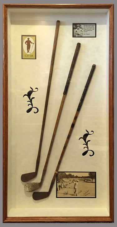 Vintage hickory shaft golf clubs in a shadow box frame with historic photos and golf club logo.