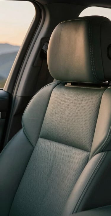 Close-up detail of a premium SUV leather interior, clean and luxurious, with soft golden-hour mountain light filtering through the window, showing comfort and elegance.