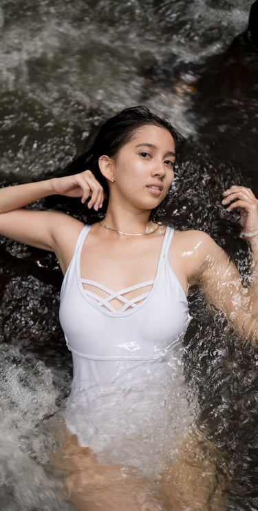 Close portrait of woman lying in flowing water during photoshoot at Kanto Lampo Bali