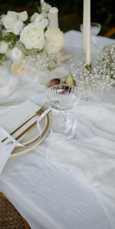 a table setting with a white table cloth and a glassware