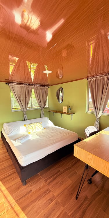 Habitación con cama doble, escritorio y grandes ventanas