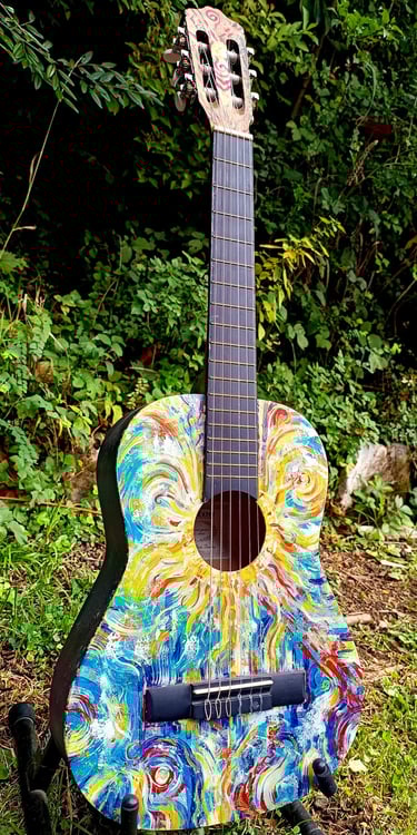 peinture sur guitare aux couleurs vives, avec un soleil autour de la rosace et des formes abstraites