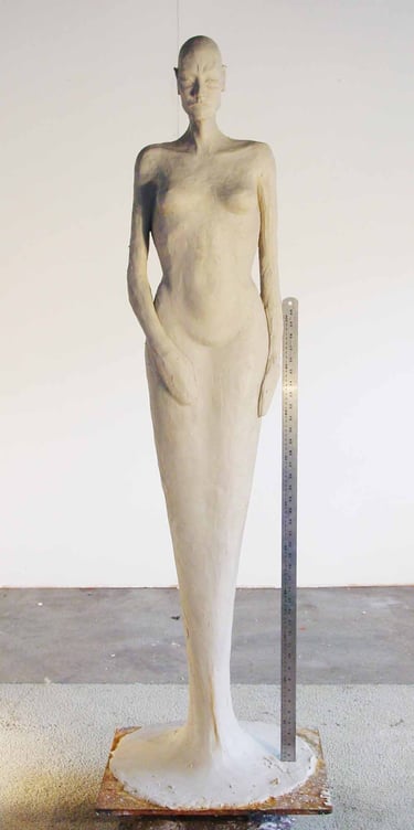 a clay model of a woman standing in a dress