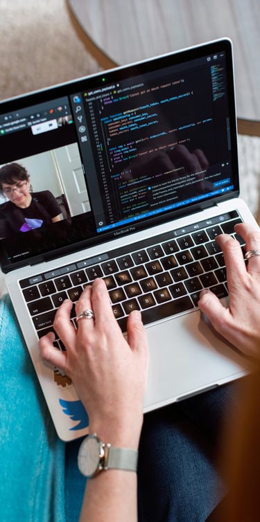 Personne tapant du code sur un ordinateur portable pendant un appel en visioconférence.
