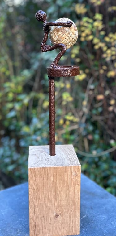 Iron sculpture with stone on wooden pedestal
