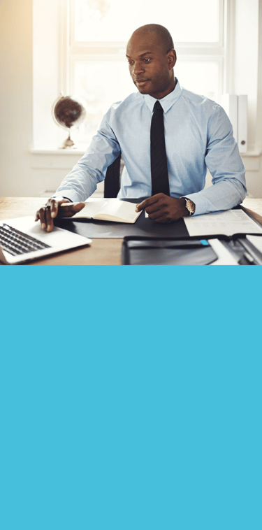 Homme en chemise bleue et cravate assis à un bureau