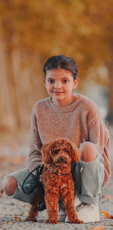bambina col proprio cane marrone sulle mura di Lucca in autunno