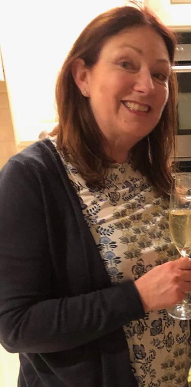 Two adults celebrating birthday in modern kitchen with champagne and cake reading 'Happy Birthday