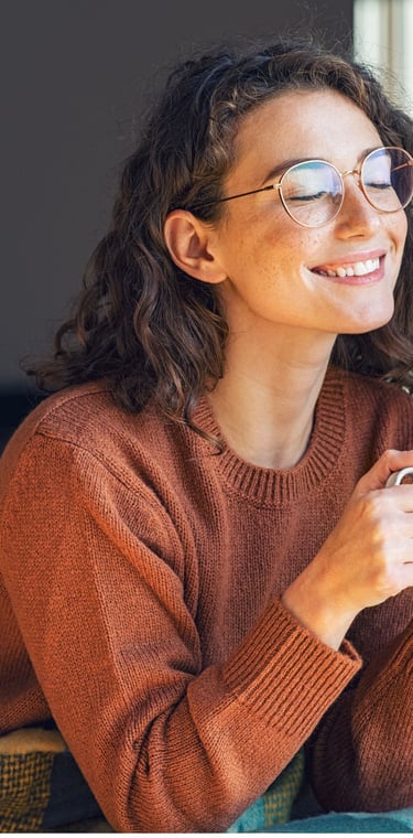 A person sitting comfortably near a window in Calgary with a cup of tea, relaxed posture