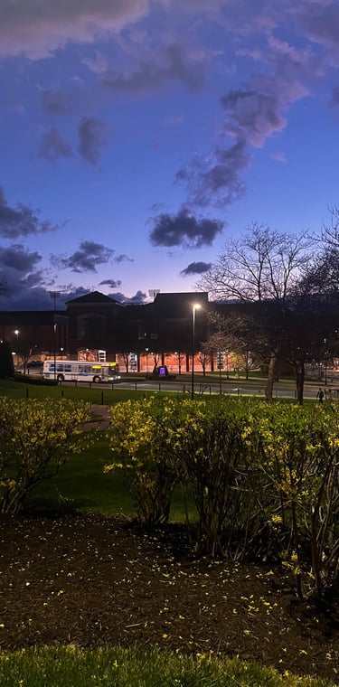 Twilight scene on a university campus with a deep blue sky, streetlights, and brick buildings