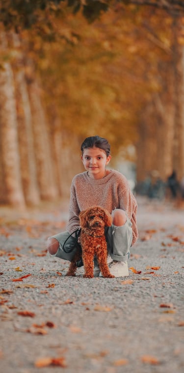 bambina col proprio cane marrone sulle mura di Lucca in autunno