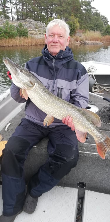 un homme est assis dans un bateau de pêche en suède, il a un beau brochet.