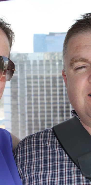 Two adults posing inside observation wheel cabin with city skyline in background, capturing a moment of leisure
