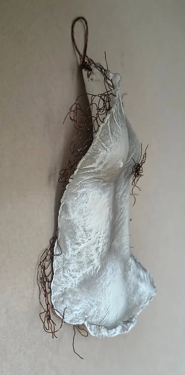 A hanging relief sculpture of a female torso with wire around it and protruding through it.