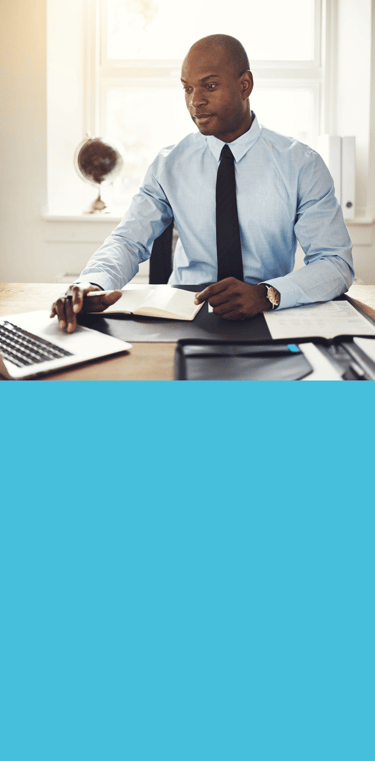 Homme en chemise bleue et cravate assis à un bureau