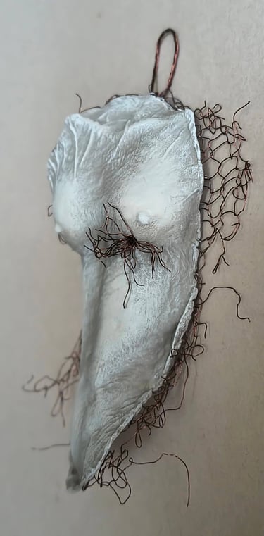 A hanging relief sculpture of a female torso with wire around it and protruding through it.