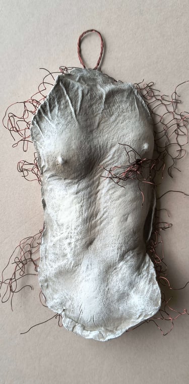 A hanging relief sculpture of a female torso with wire around it and protruding through it.