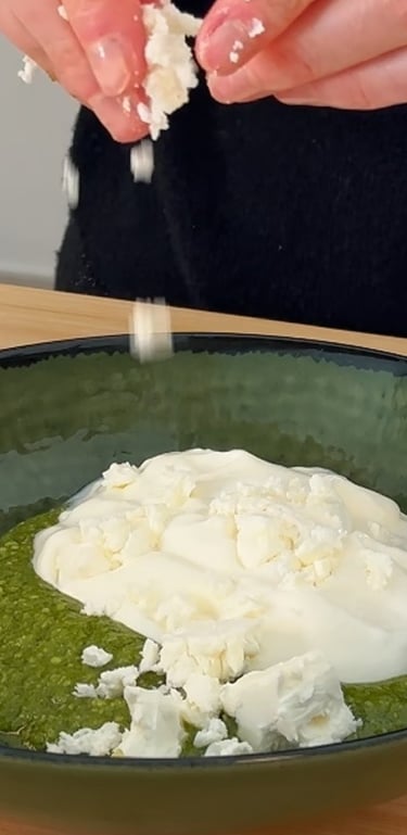 Unisci il pesto di basilico, la feta sbriciolata e la panna acida