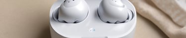 A pair of wireless earbuds resting on a wooden table with charging case.
