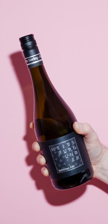 Pinot Blanc bottle photographed on a pink background.