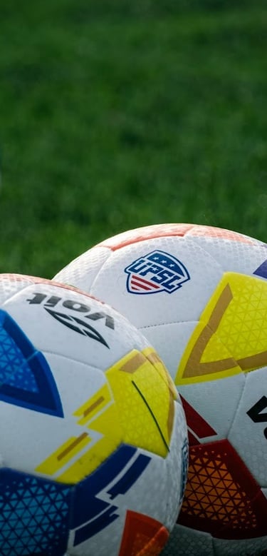 three soccer balls on a field with a soccer ball