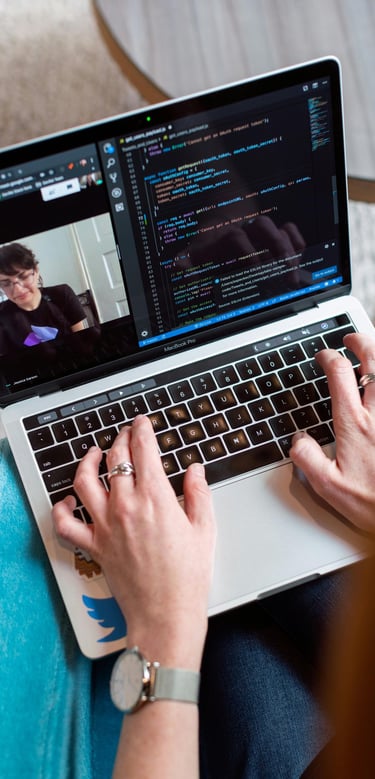 Personne tapant du code sur un ordinateur portable pendant un appel en visioconférence.