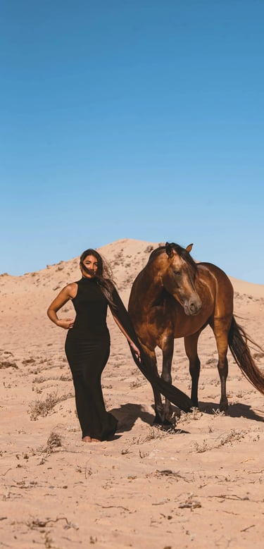 Editorial photography in Dakhla desert with a fashion model and a brown horse against a clear blue Sahara sky.