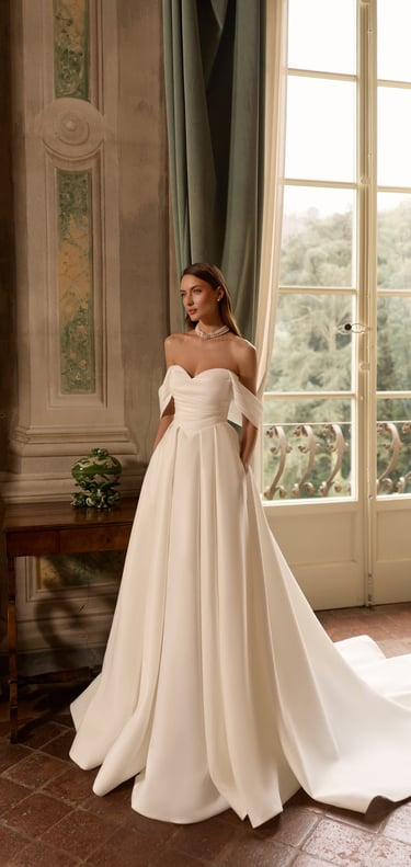 Elegant bride in an off-the-shoulder ball gown wedding dress with a sweetheart neckline.