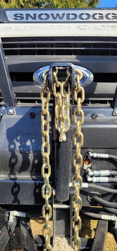 a close up picture of the front of a truck with chains for a plow blade