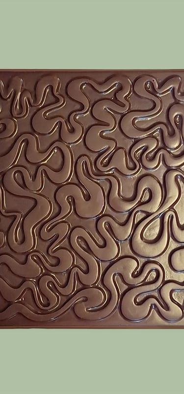 A square dark chocolate bar with an intricate, wavy embossed maze pattern on a light green background.
