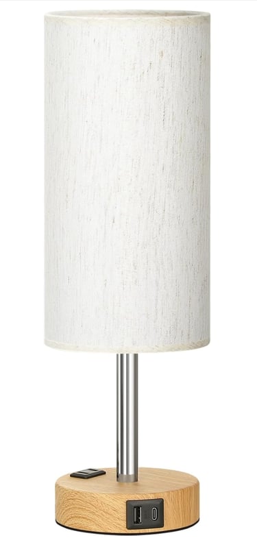 Modern bedside table lamp with wood base, fabric shade, and built-in USB charging ports.