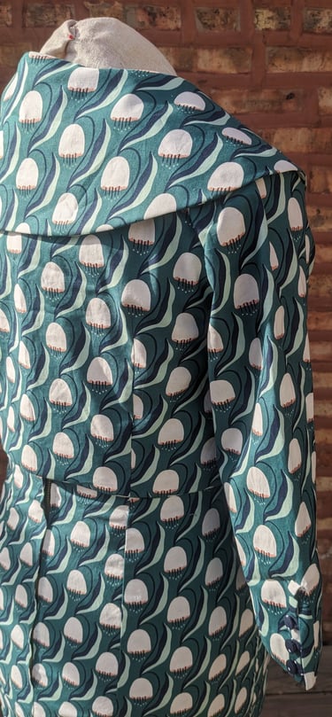 The back of a green art nouveau reversible sheath dress and 50's inspired cropped jacket