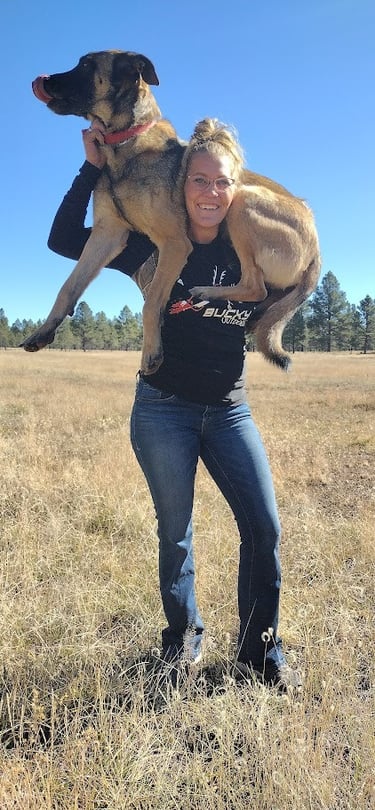 a woman holding a dog in a field