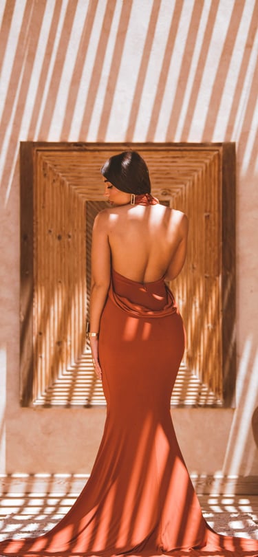 High-fashion portrait in Dakhla showing geometric shadow play on a resort wall with a model in an elegant backless dress.