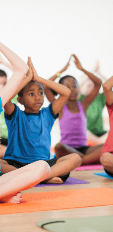 Children group yoga with rainbow colored mats